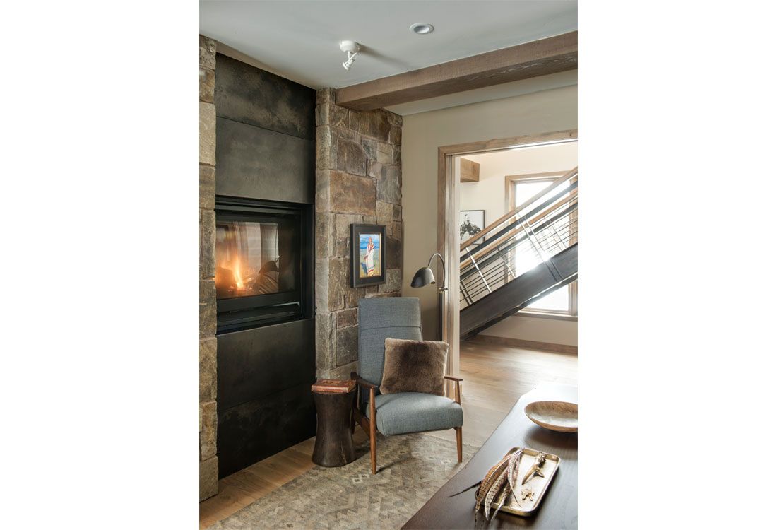 A living room with a fireplace , chair , table and stairs.