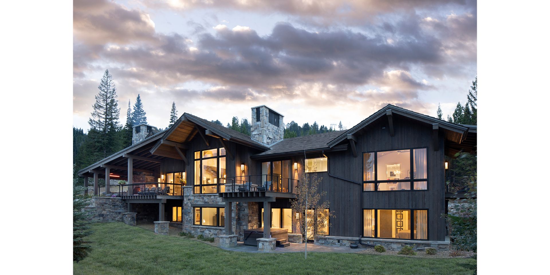 A large house with a lot of windows is in the middle of a forest.