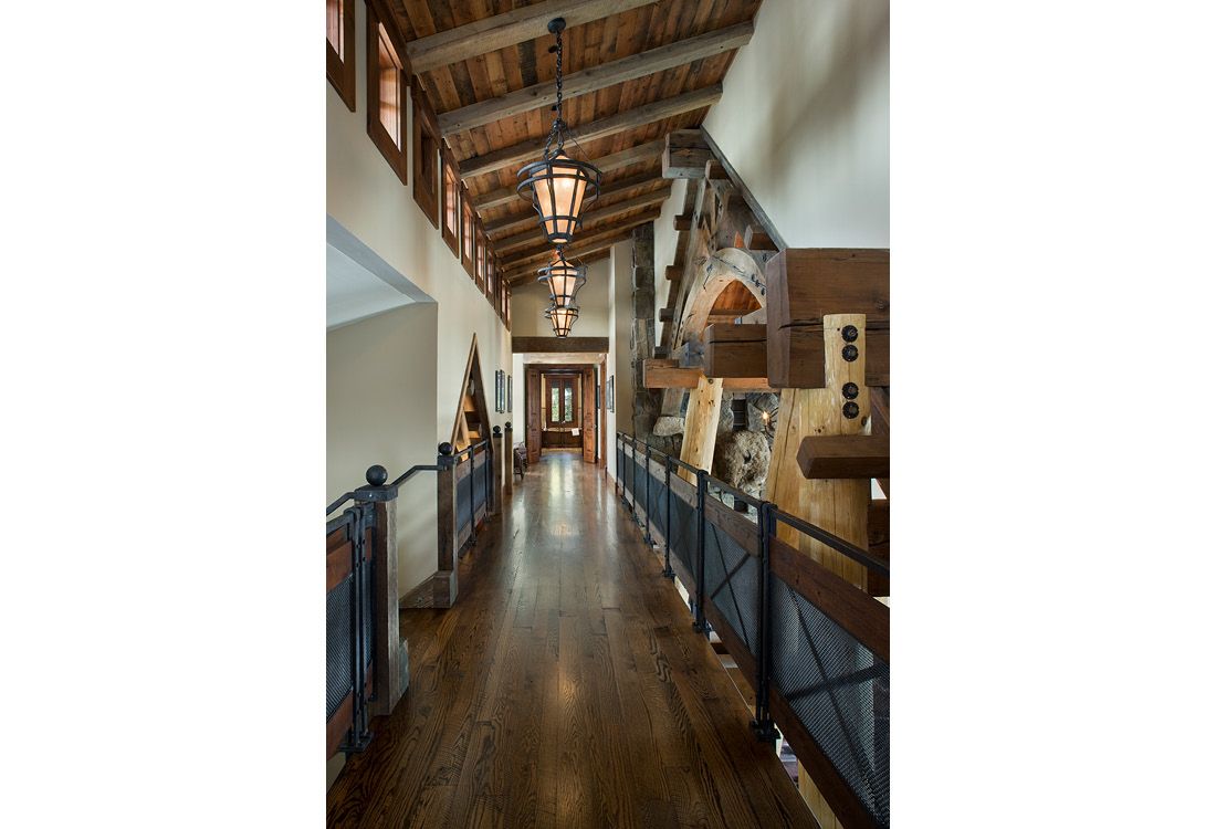 A long hallway with wooden floors and a wooden ceiling in a house.