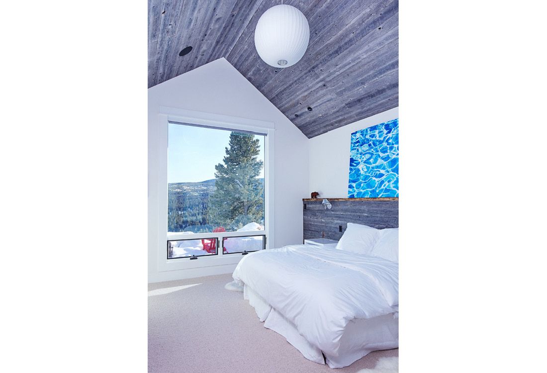 A bedroom with a bed and a large window.