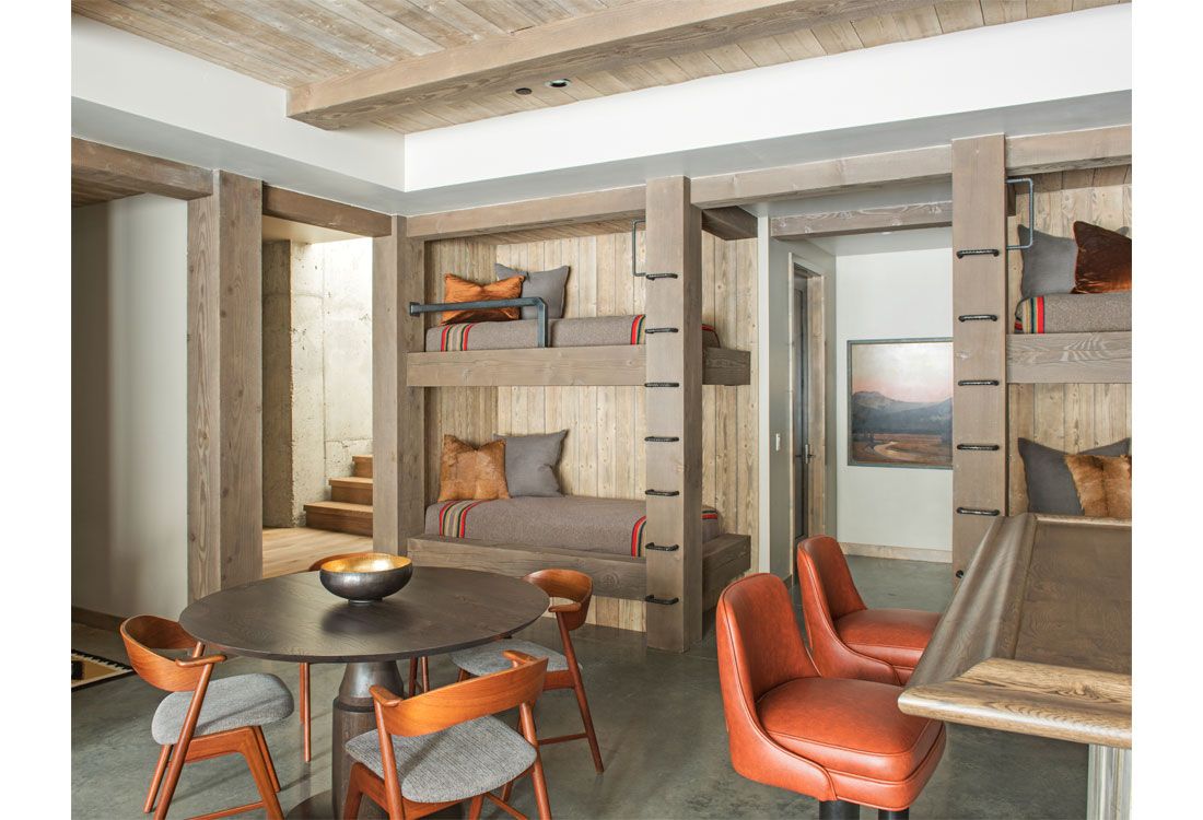 A room with bunk beds , a table and chairs.