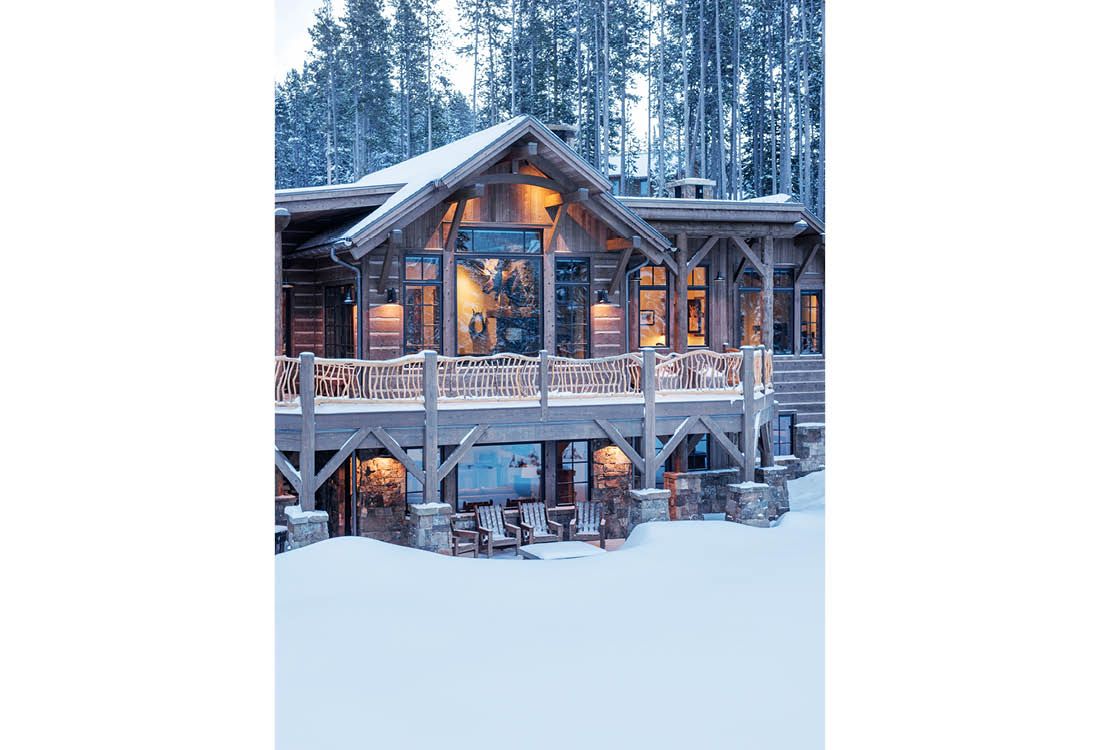 A large wooden house in the middle of a snowy forest.