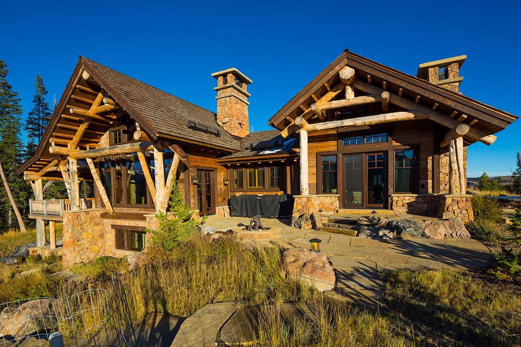 A large log cabin is sitting in the middle of a grassy field.