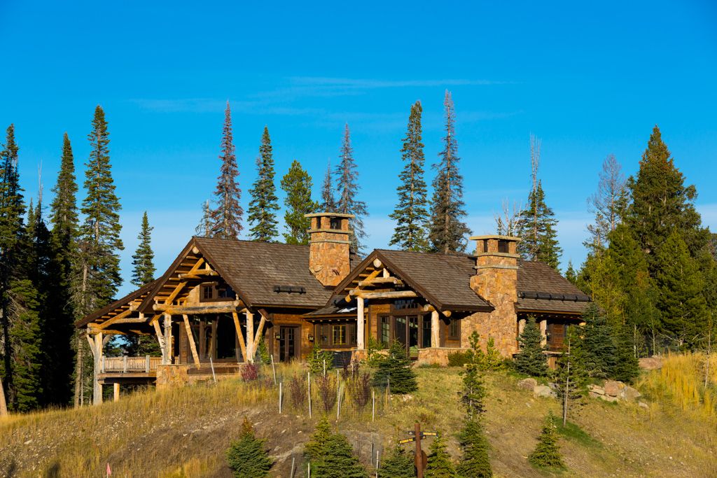 A large house is sitting on top of a hill surrounded by trees.