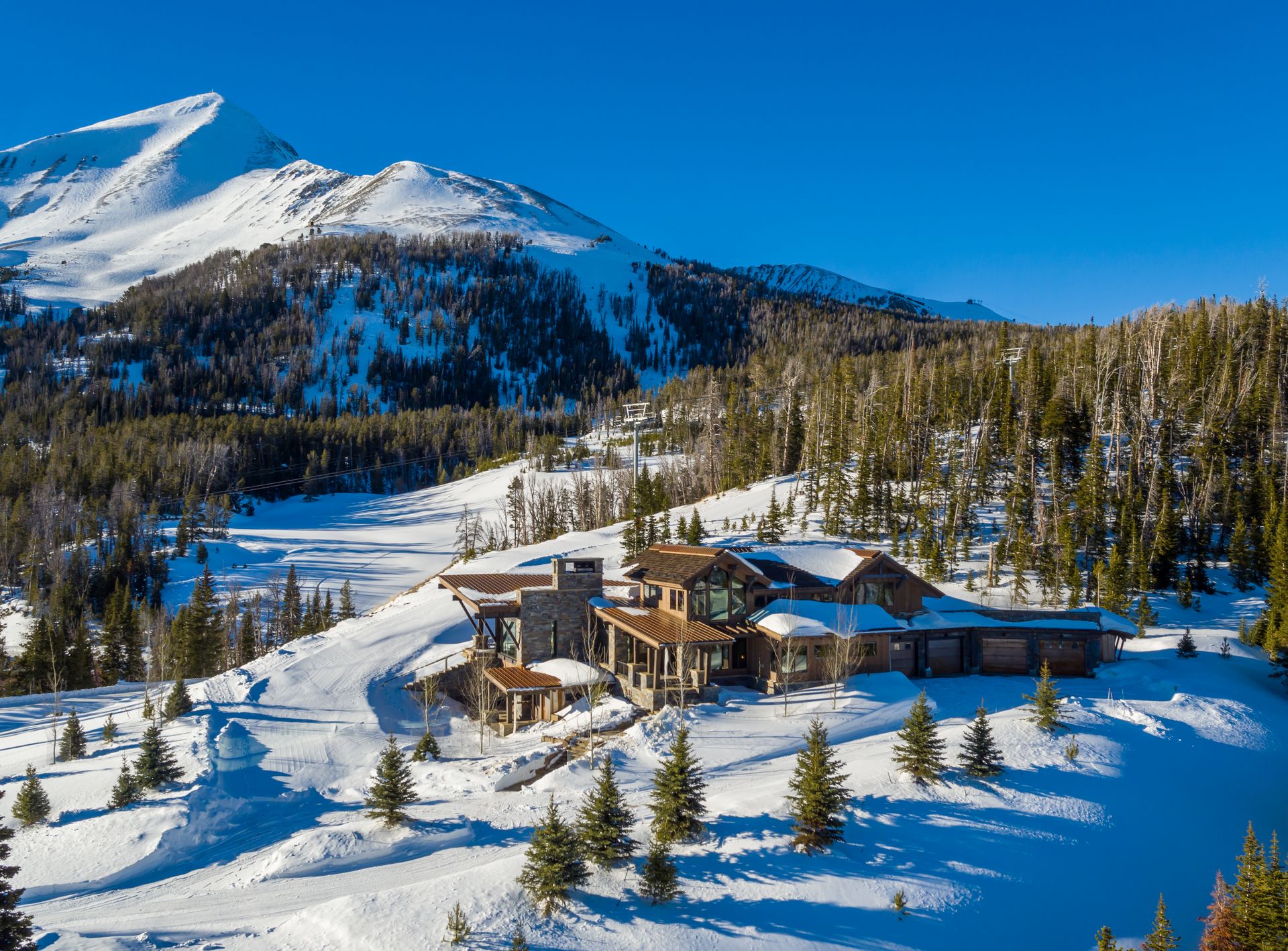 An aerial view of a house in the middle of a snowy mountain.
