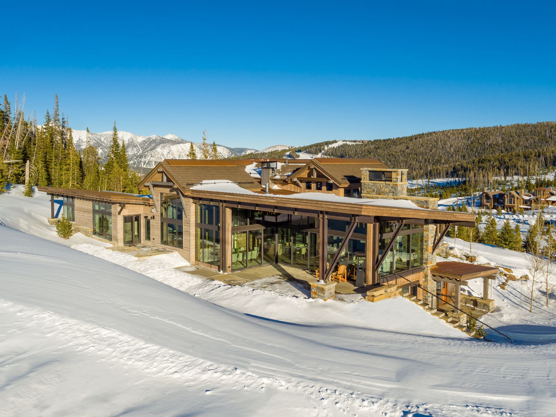 A large house is sitting on top of a snow covered hill.