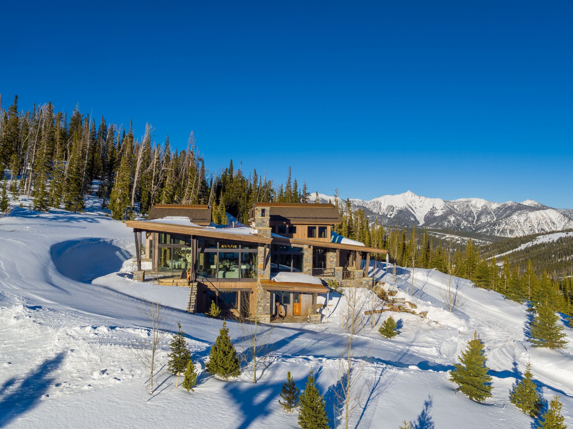 A large house is sitting on top of a snow covered hill.