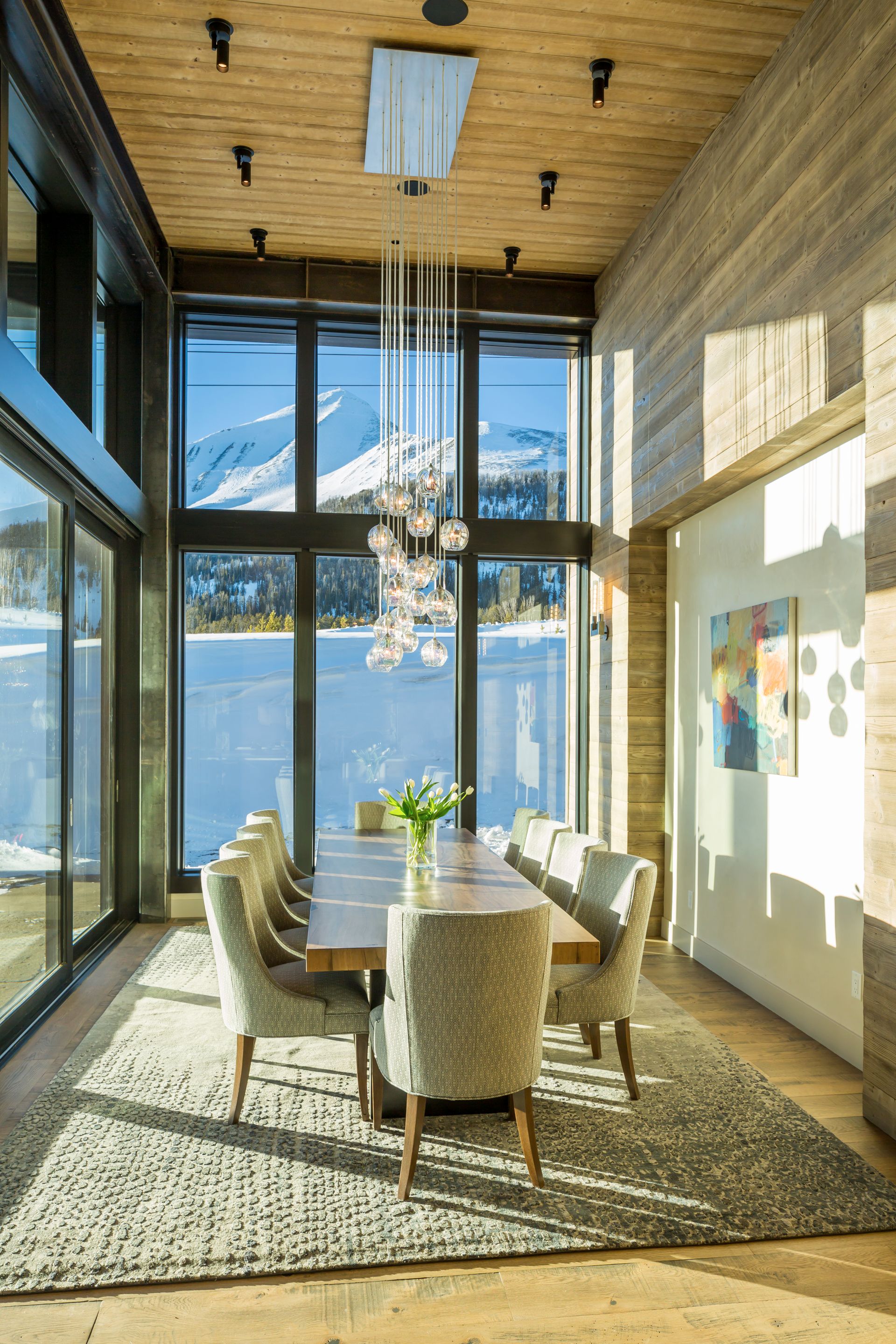 A dining room with a long table and chairs and a chandelier.