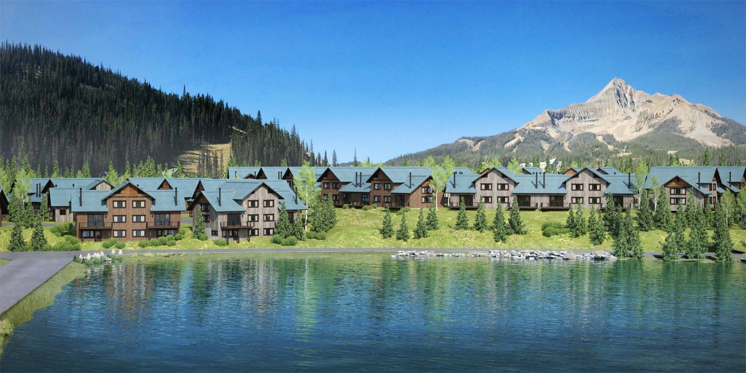 A row of houses sitting next to a lake with a mountain in the background.