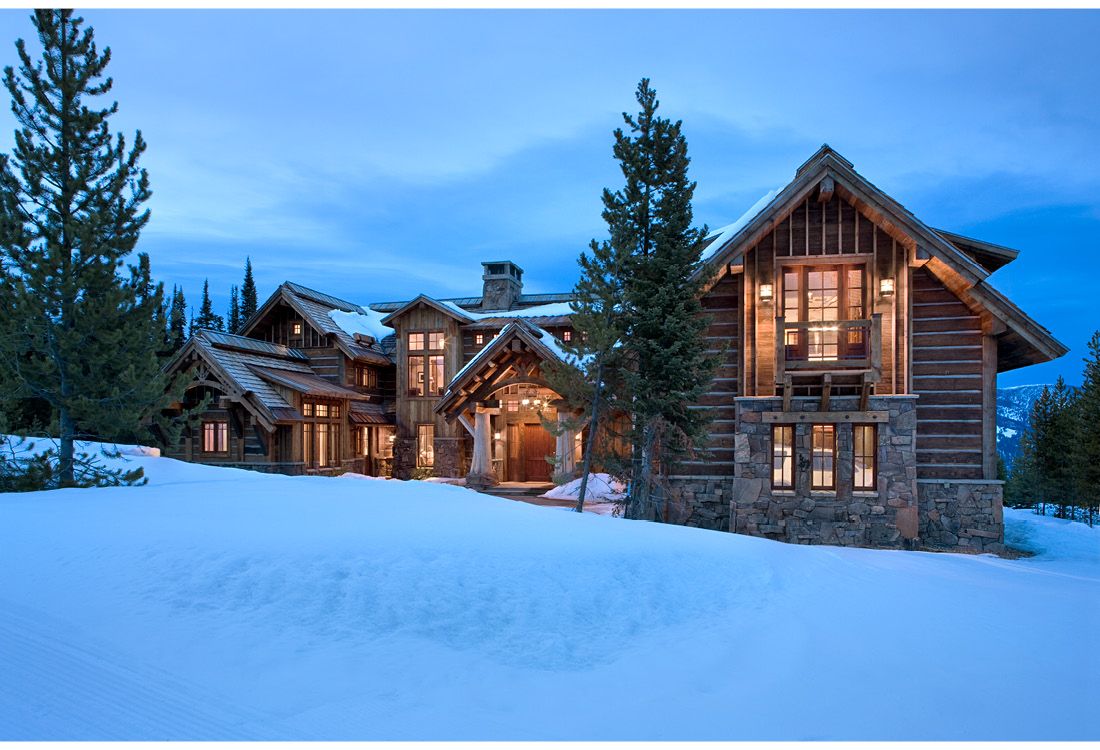 A large log cabin in the middle of a snowy field
