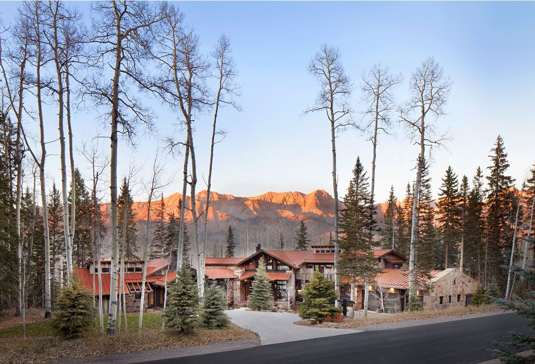 A house in the middle of a forest with a mountain in the background.