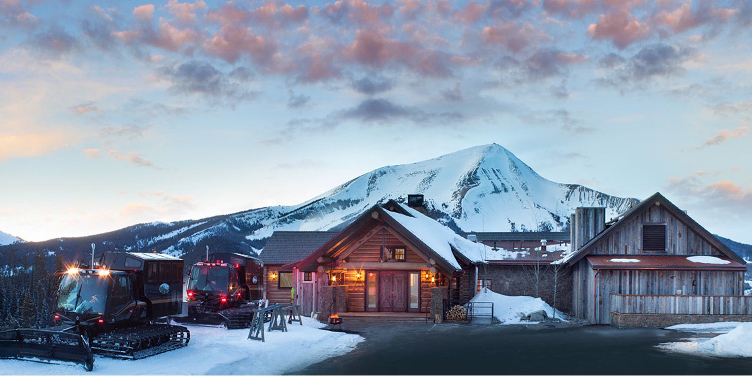 A house with a mountain in the background is covered in snow.