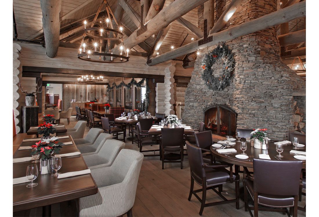 A large dining room with tables and chairs and a fireplace.