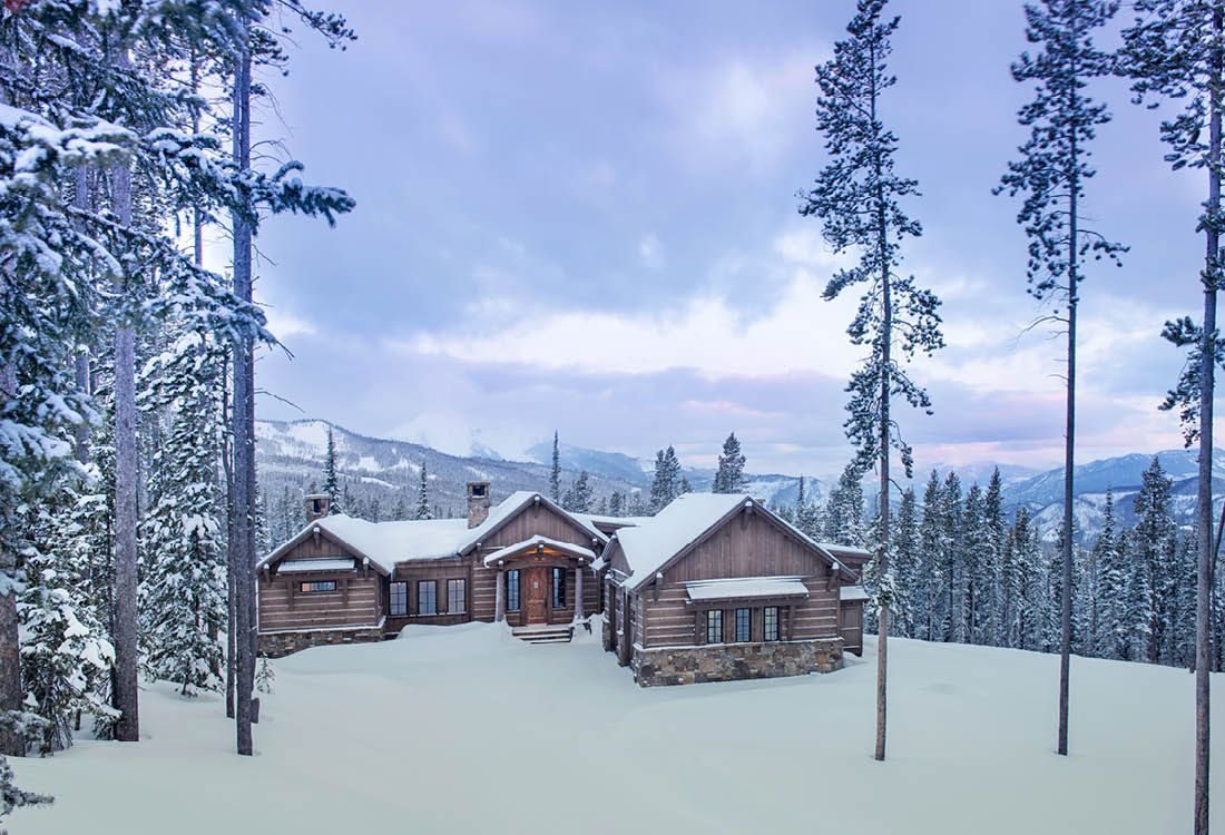 A large log cabin in the middle of a snowy forest.