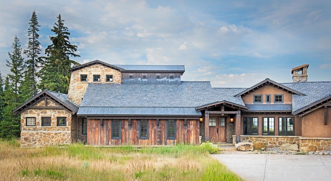 A large house with a blue roof is sitting in the middle of a field.