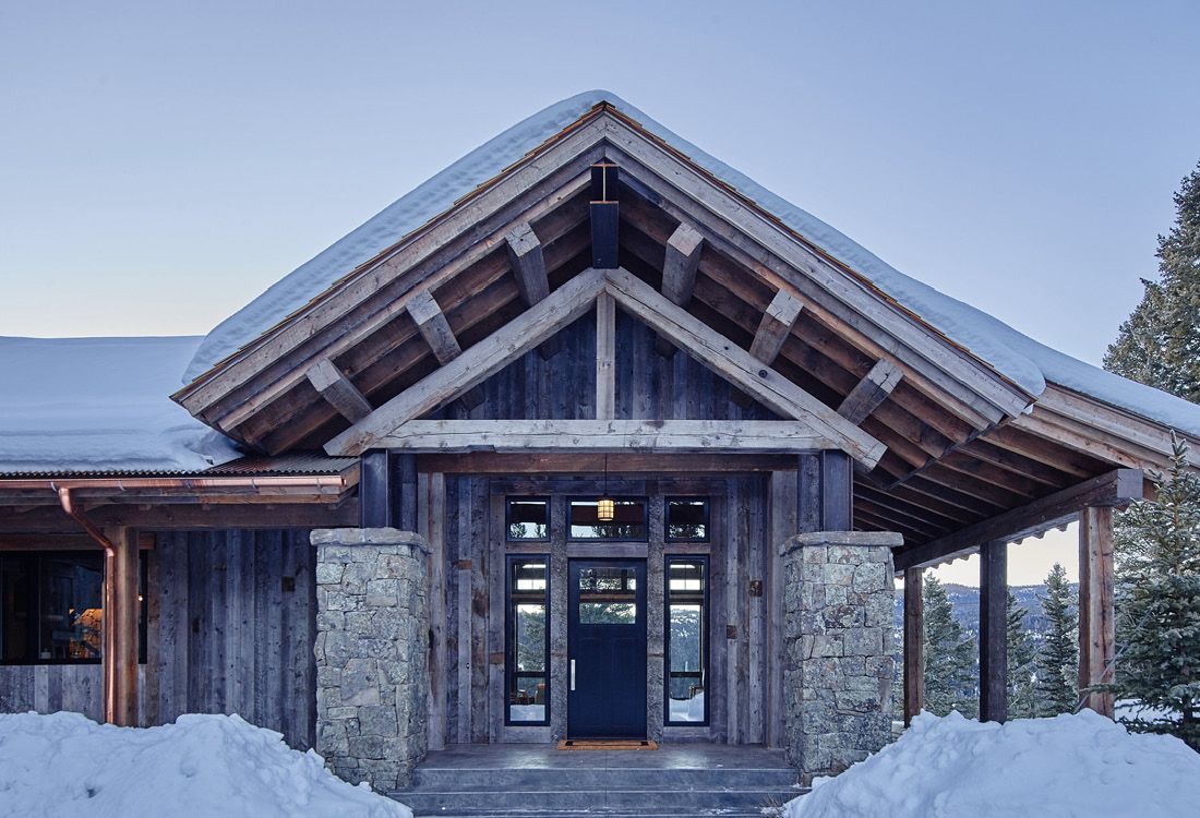 A snowy house with a wooden roof and a blue door