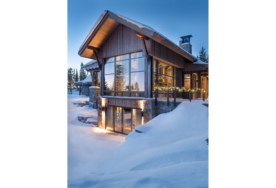 A large house with a lot of windows is surrounded by snow.