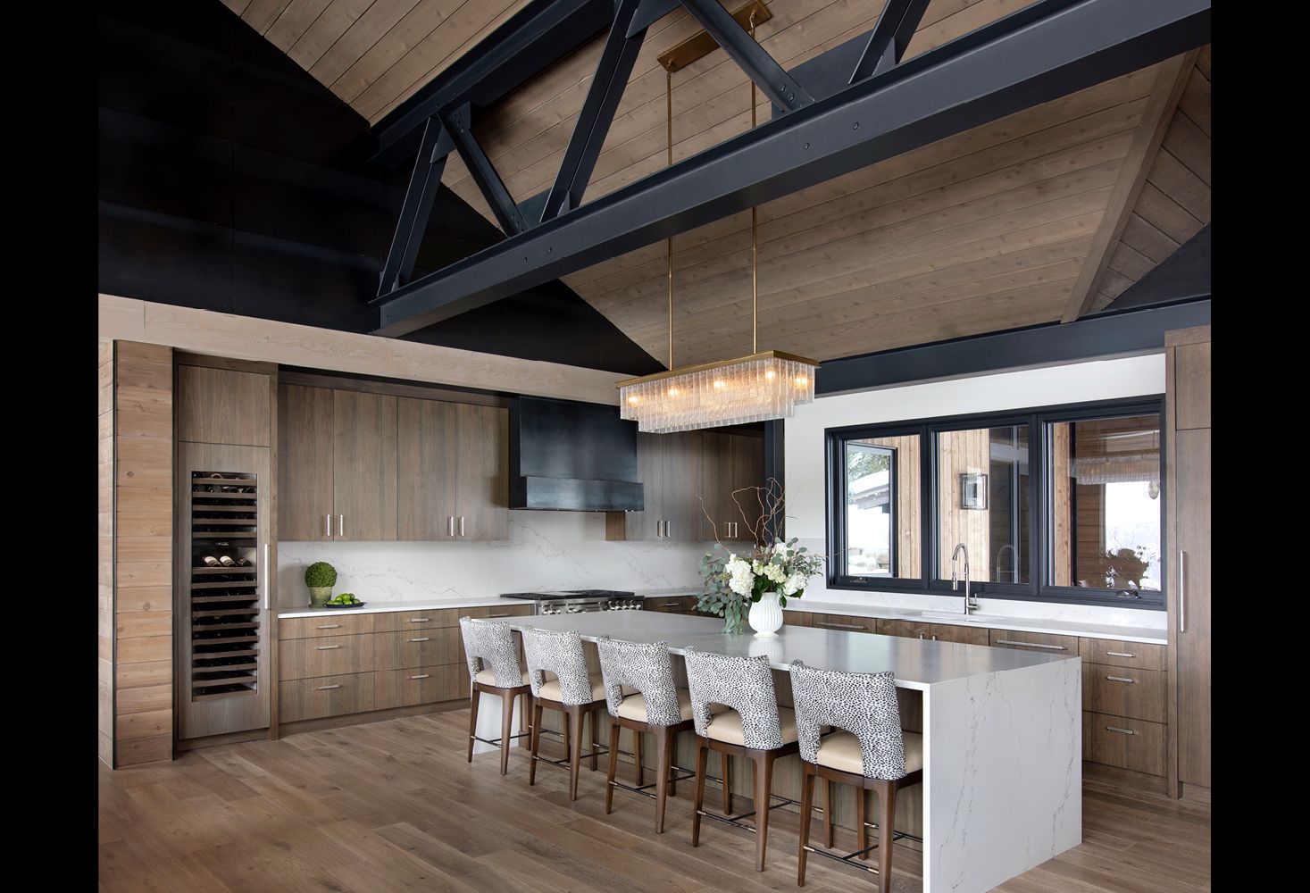 A kitchen with wooden cabinets , a large island , and a chandelier hanging from the ceiling.