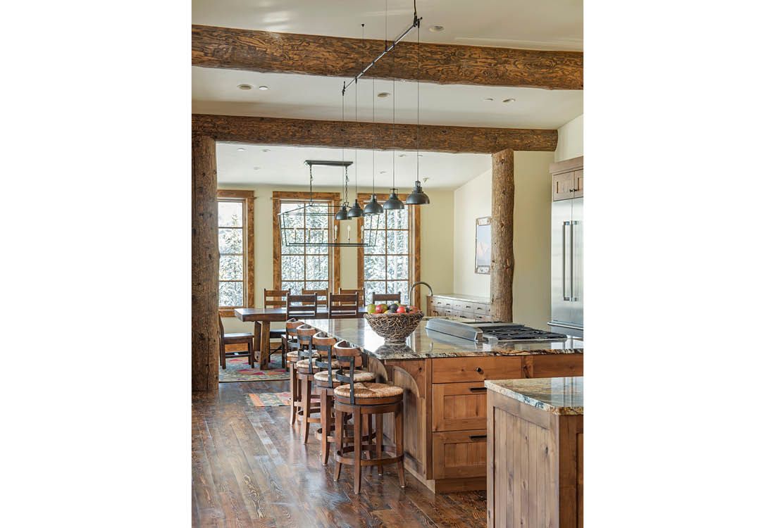 A kitchen and dining room in a house with wooden beams.
