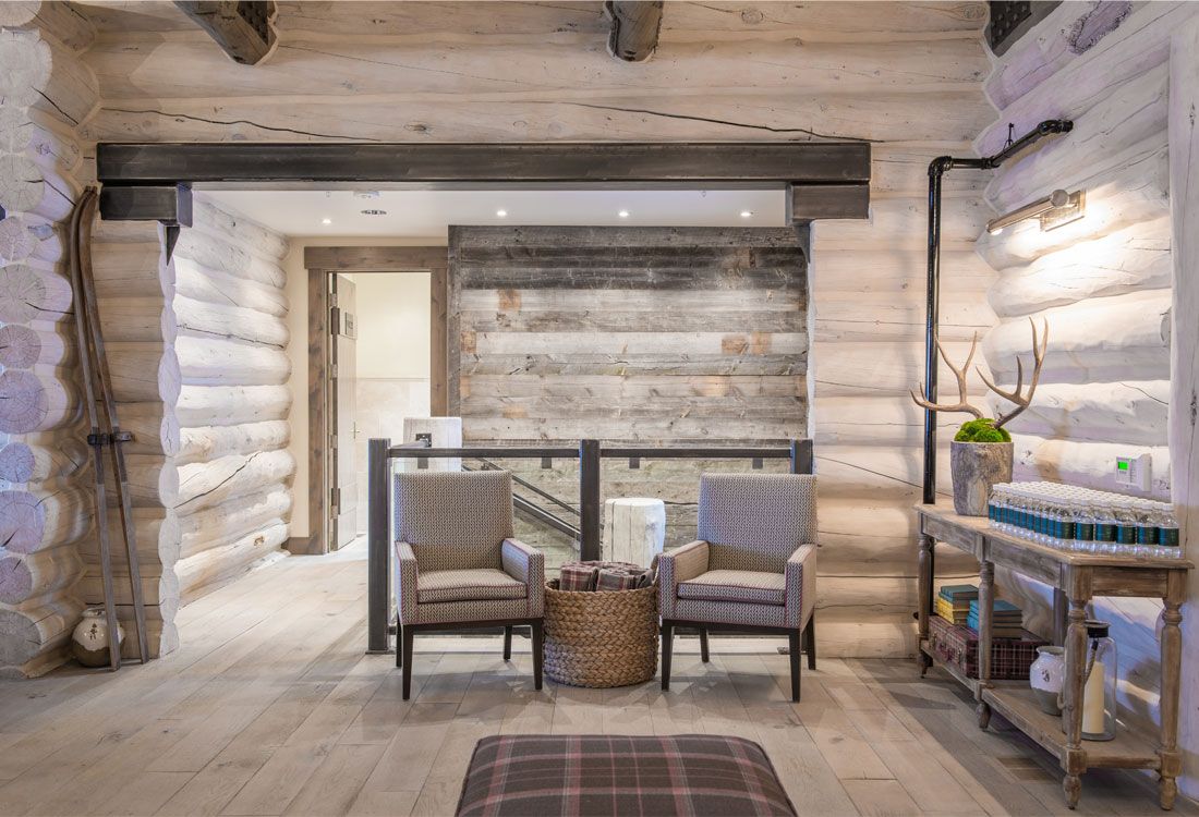 A living room in a log cabin with two chairs and a table.