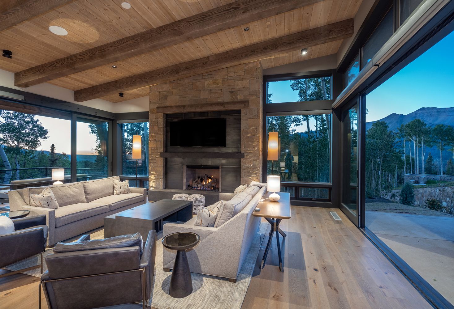 A living room with a fireplace , couch , chairs , table and television.