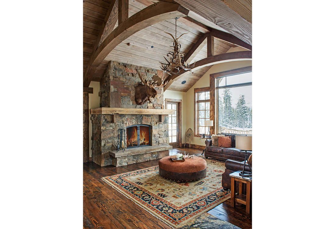 A living room with a fireplace and a deer head on the ceiling.