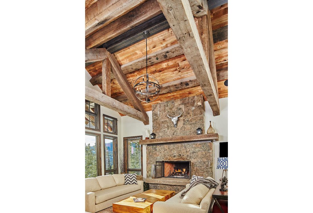 A living room with a couch , fireplace , and wooden beams.