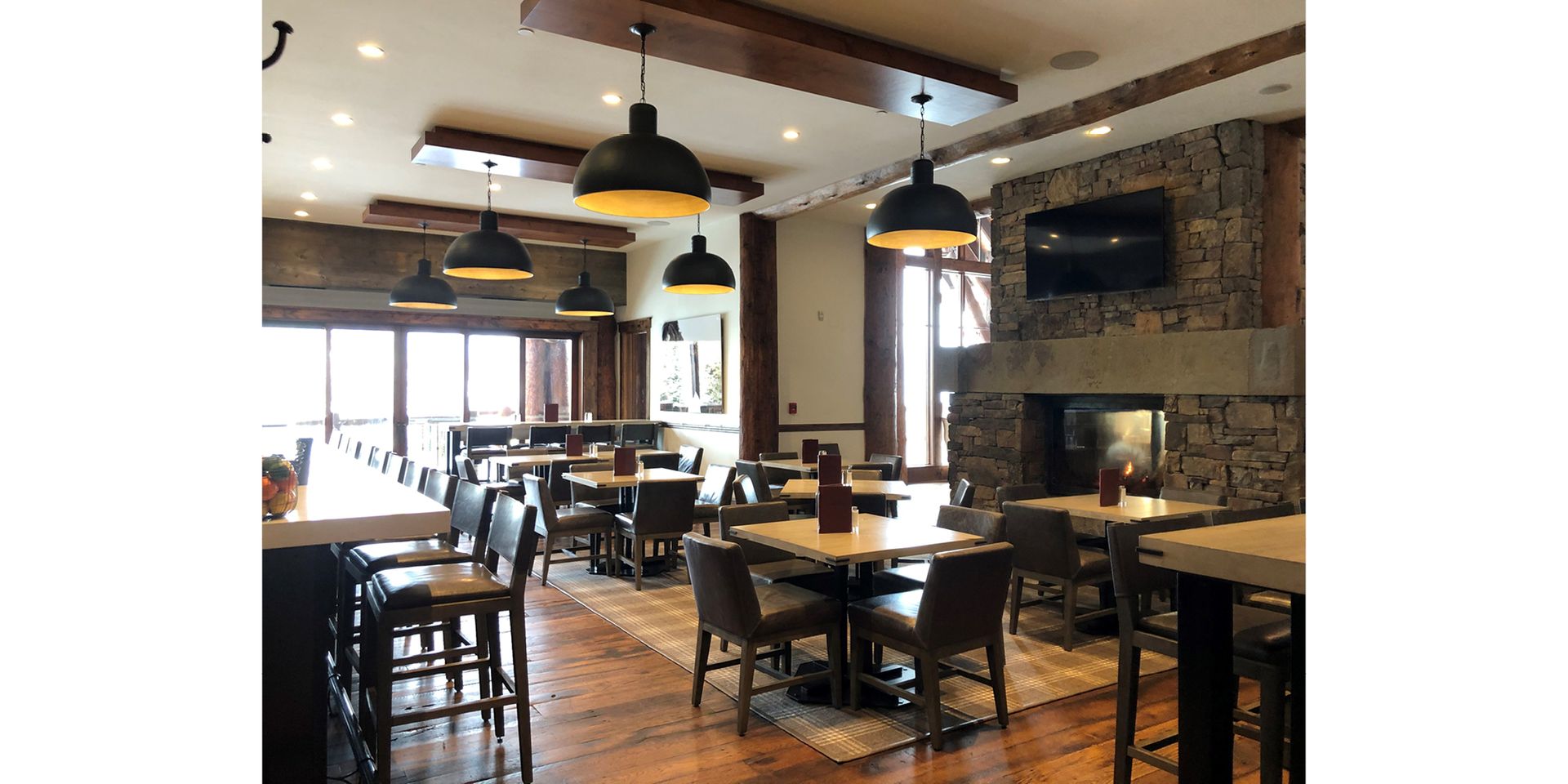 A restaurant with tables and chairs and a fireplace.