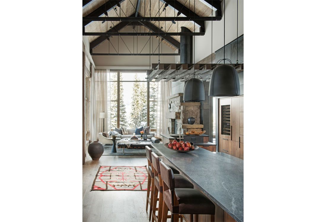 A kitchen with a long counter and stools and a large window.