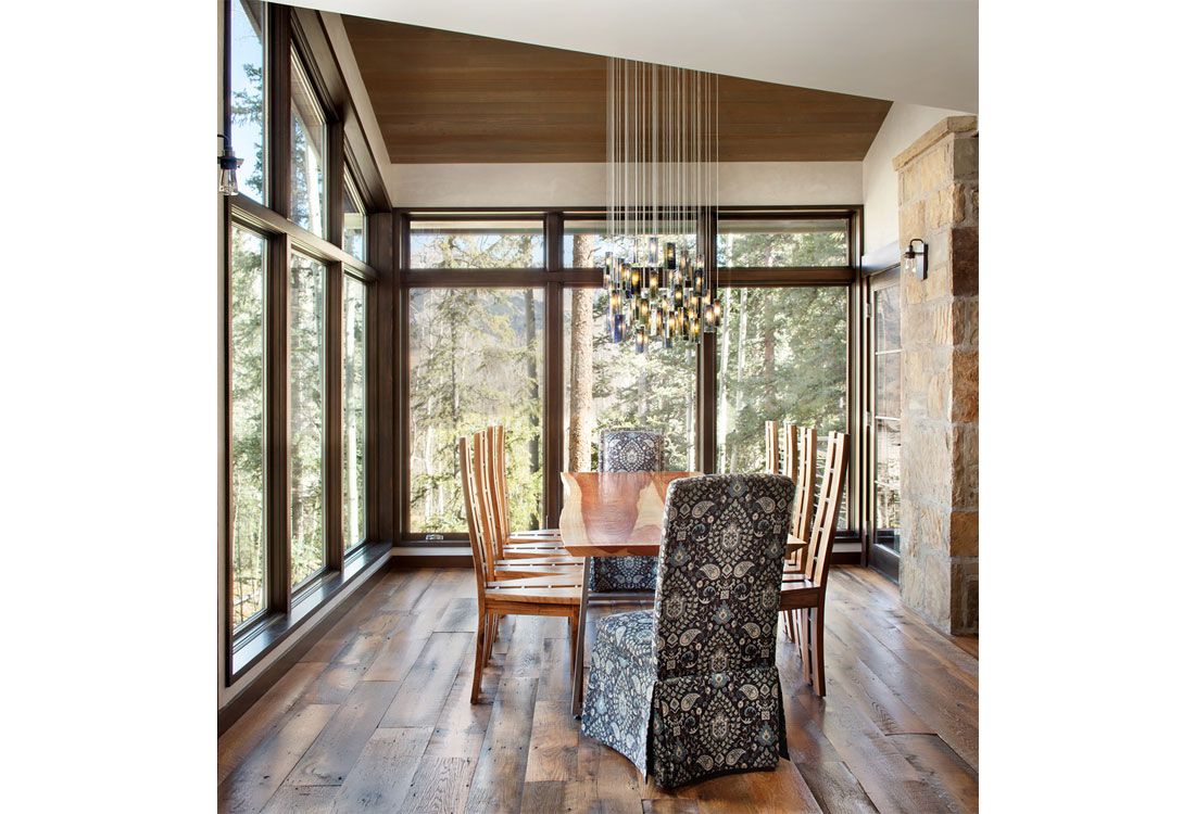A dining room with a table and chairs and lots of windows.
