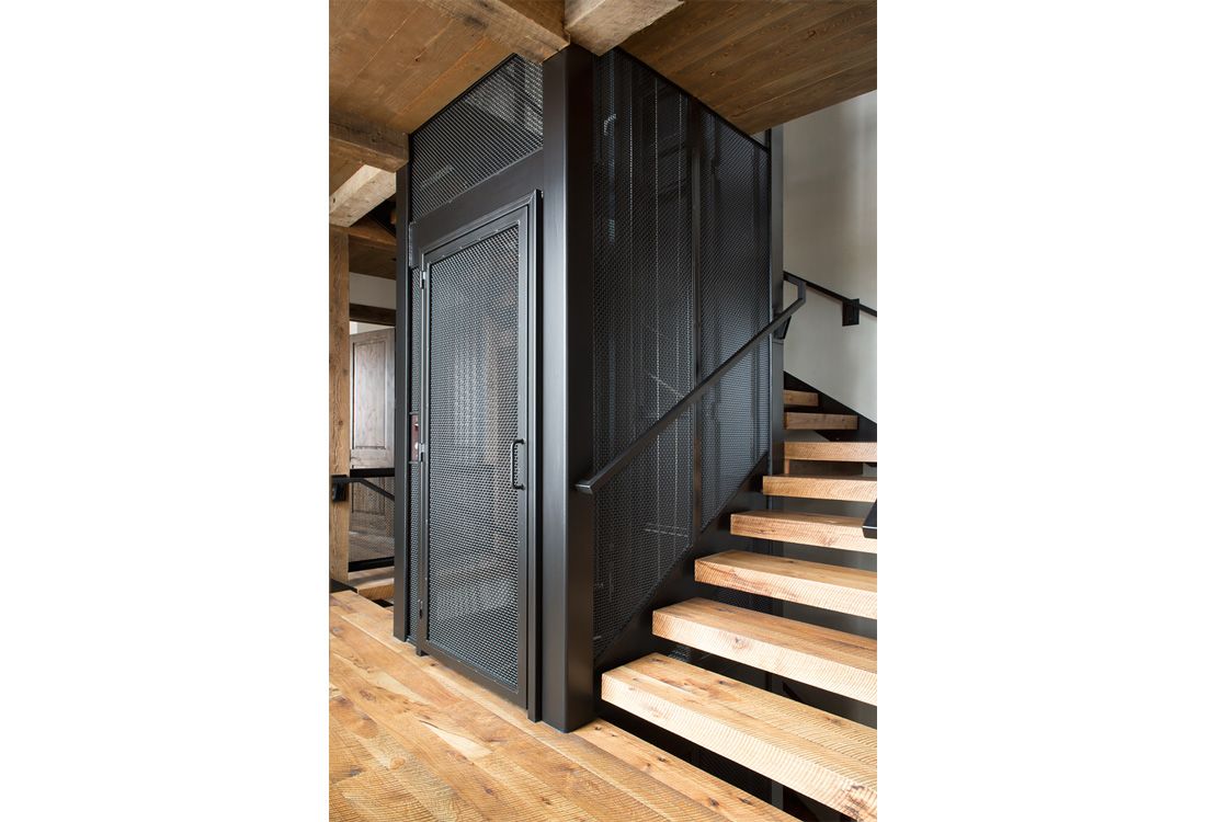 A wooden staircase with a metal door and railing.