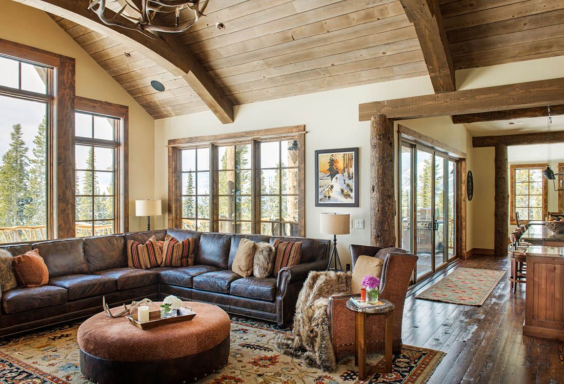 A living room with a large sectional couch and a round ottoman.