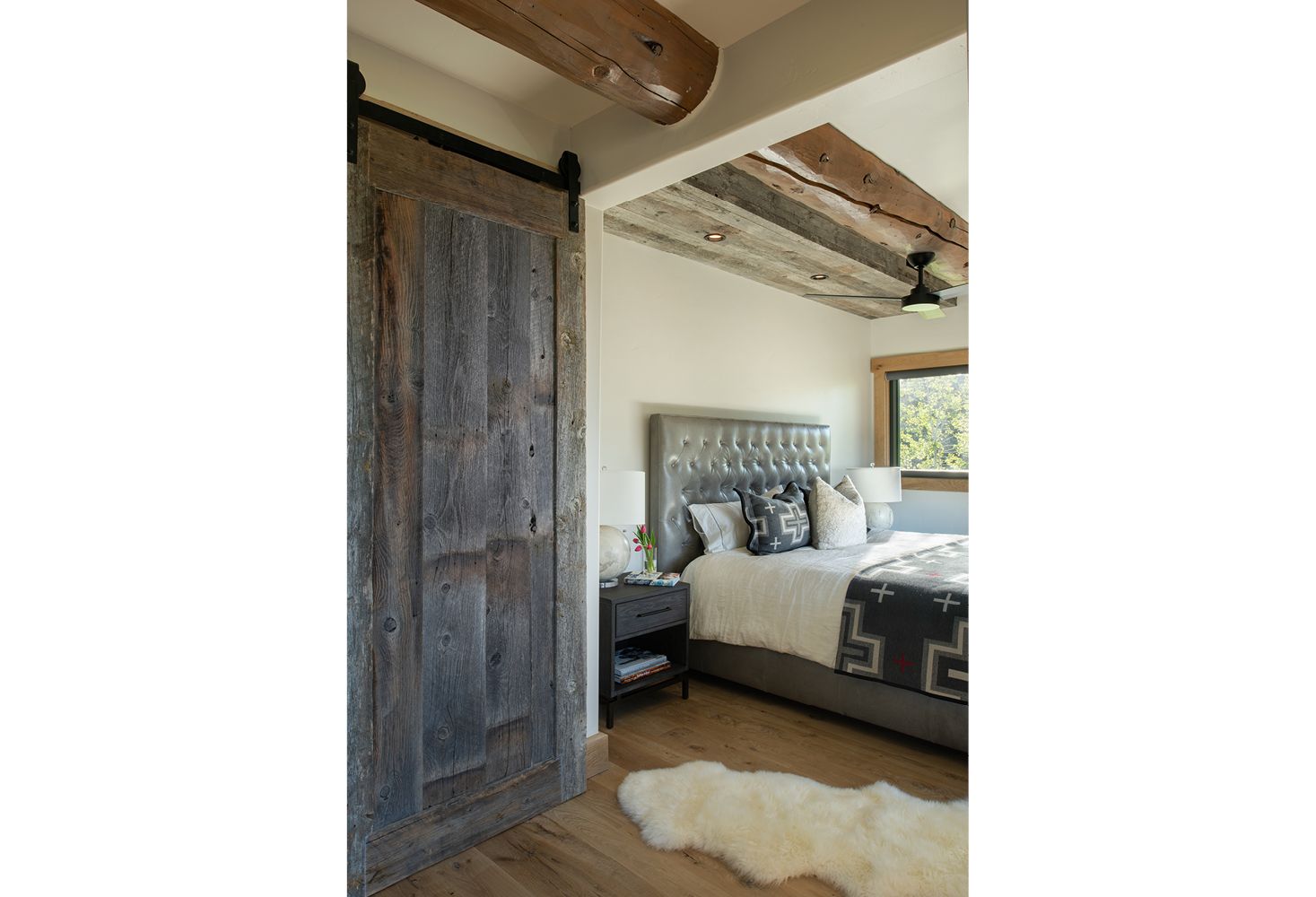 A bedroom with a sliding barn door and a bed.
