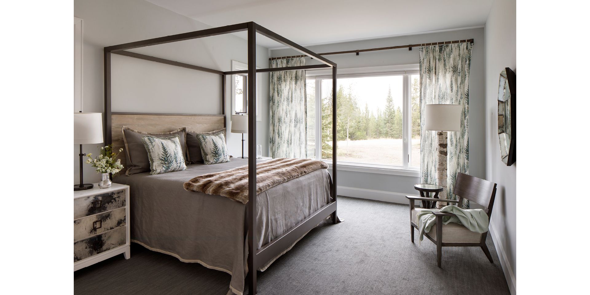 A bedroom with a canopy bed and a large window.