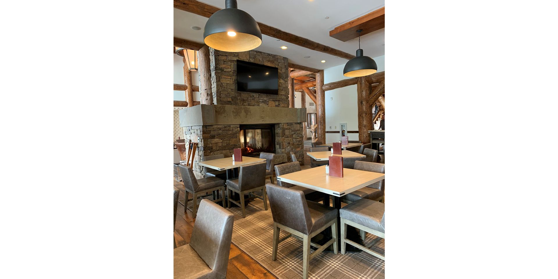 A restaurant with tables and chairs and a fireplace.