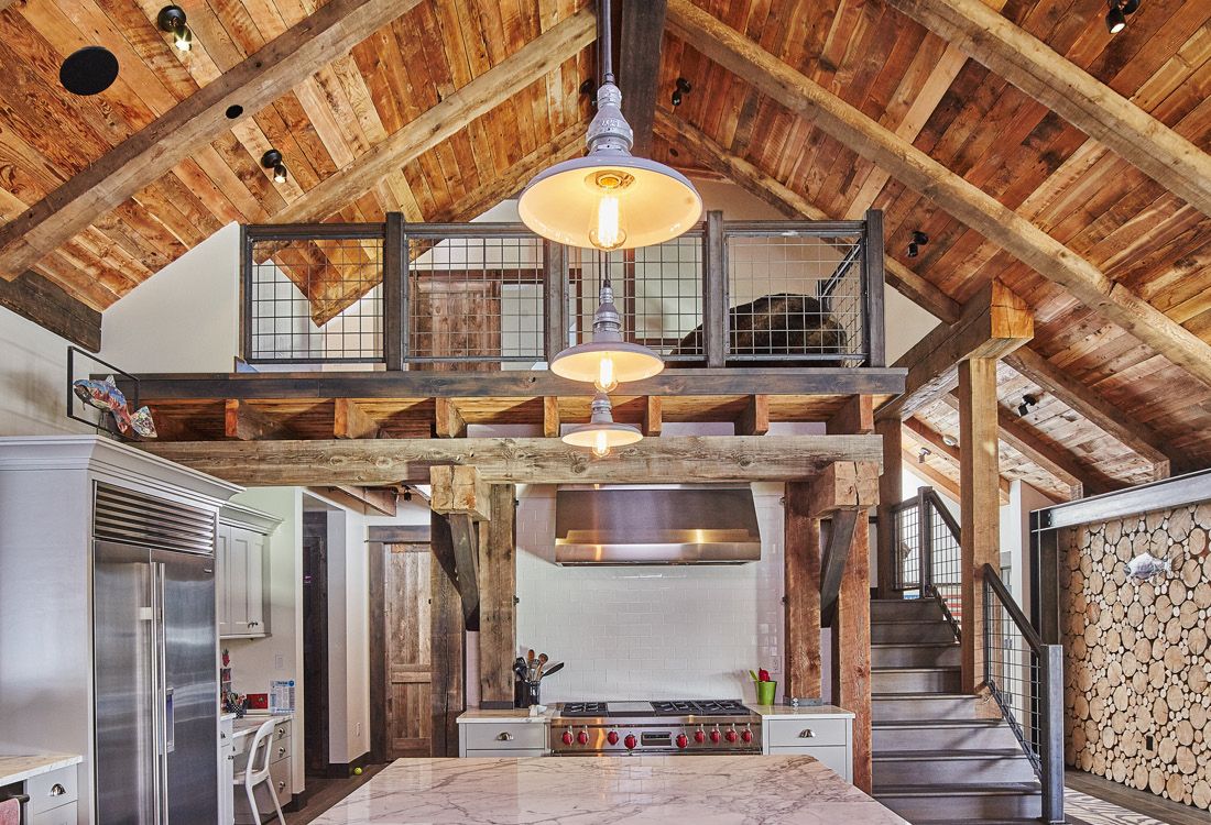 A kitchen with a wooden ceiling and stairs leading to the second floor.