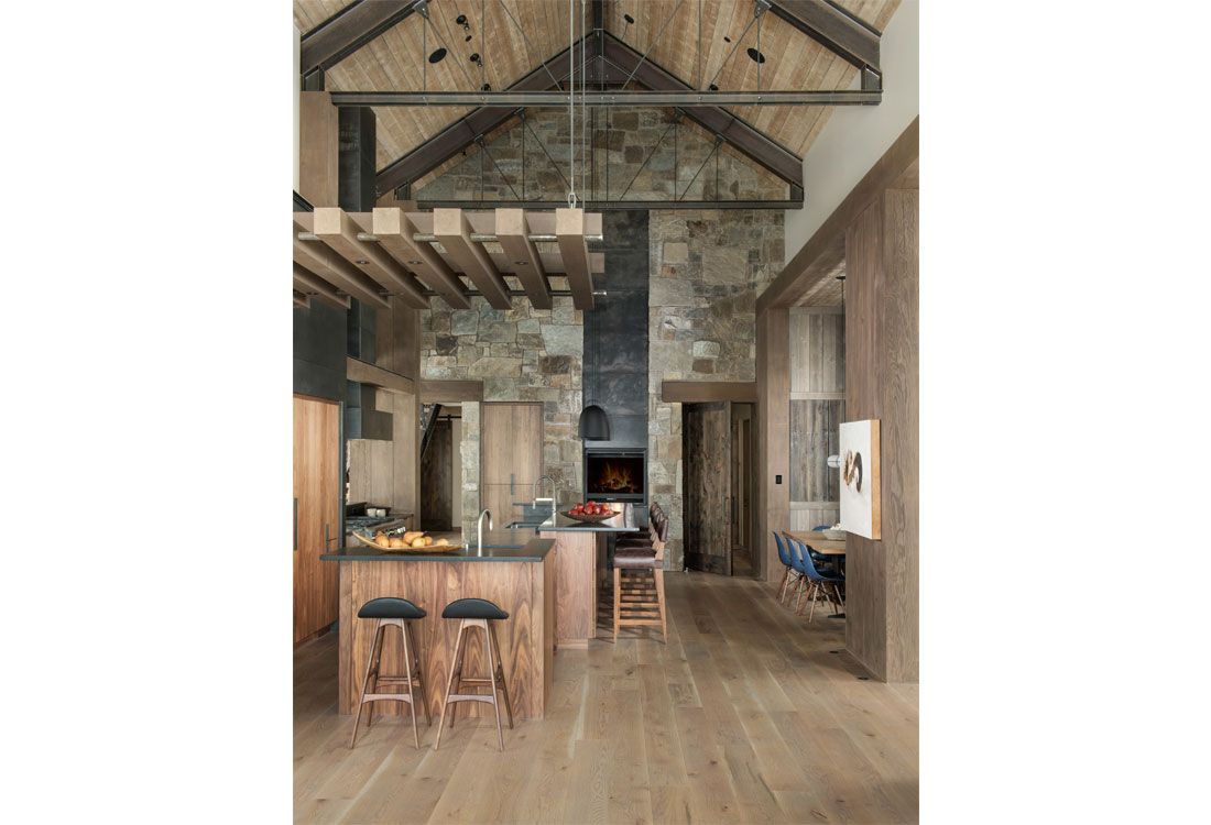 A kitchen with a large island and stools in a house.