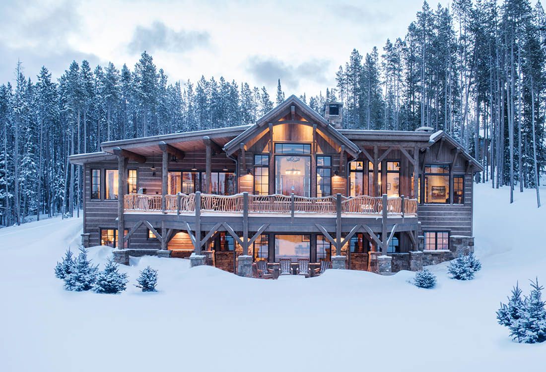 A large wooden house in the middle of a snowy forest.