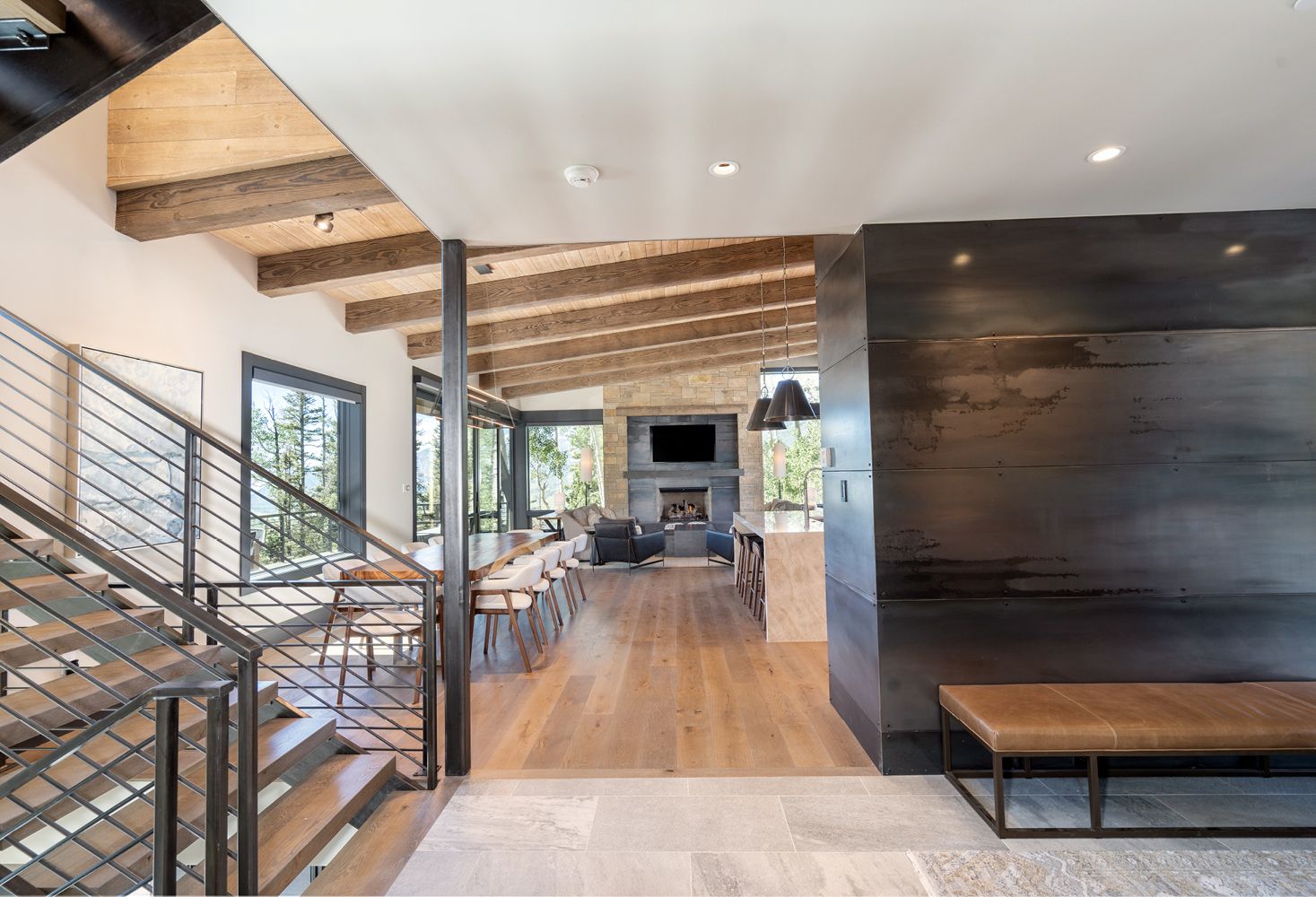 A living room with a staircase leading to the second floor and a bench.