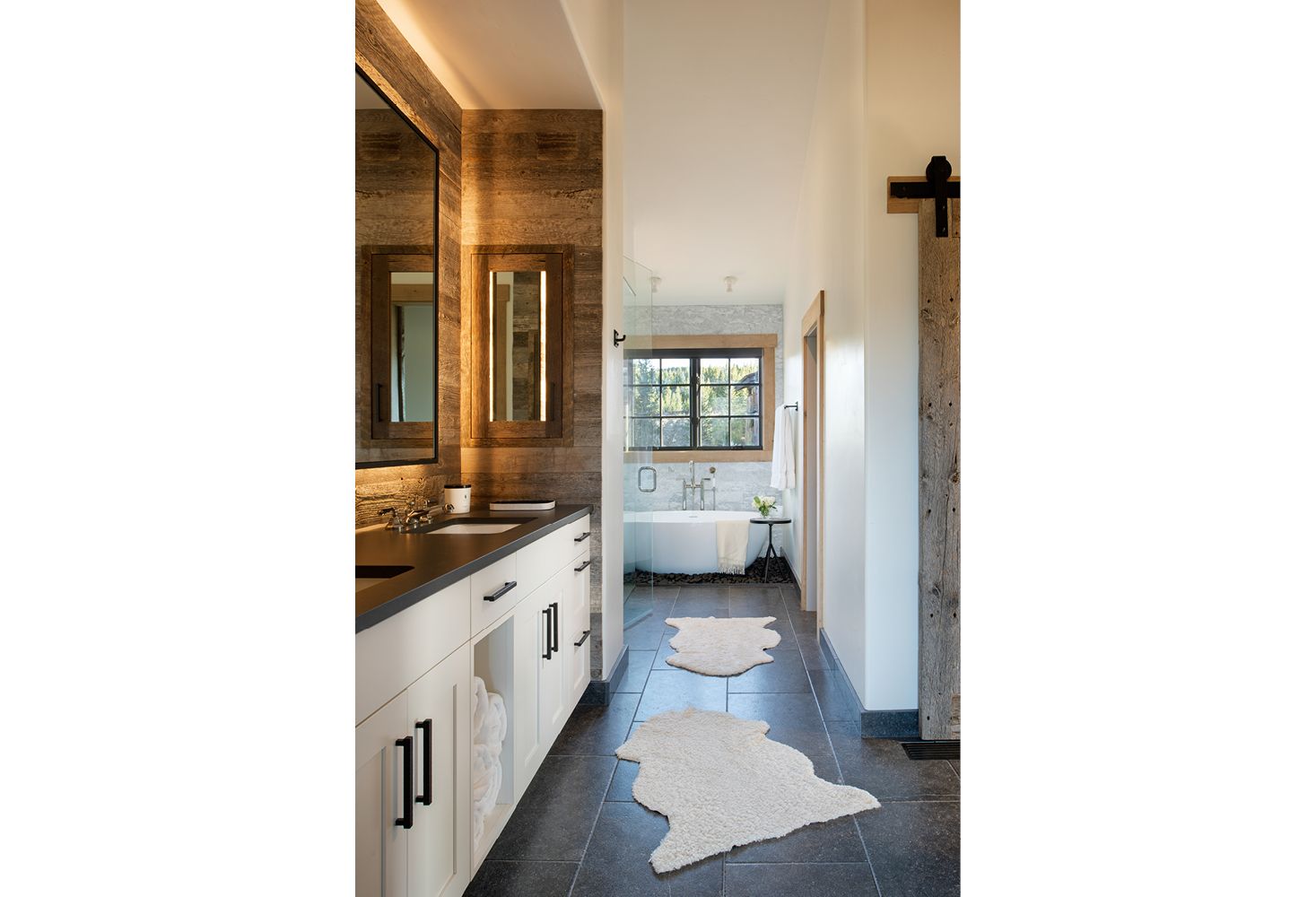 A bathroom with two sinks , a tub , a mirror and a rug.