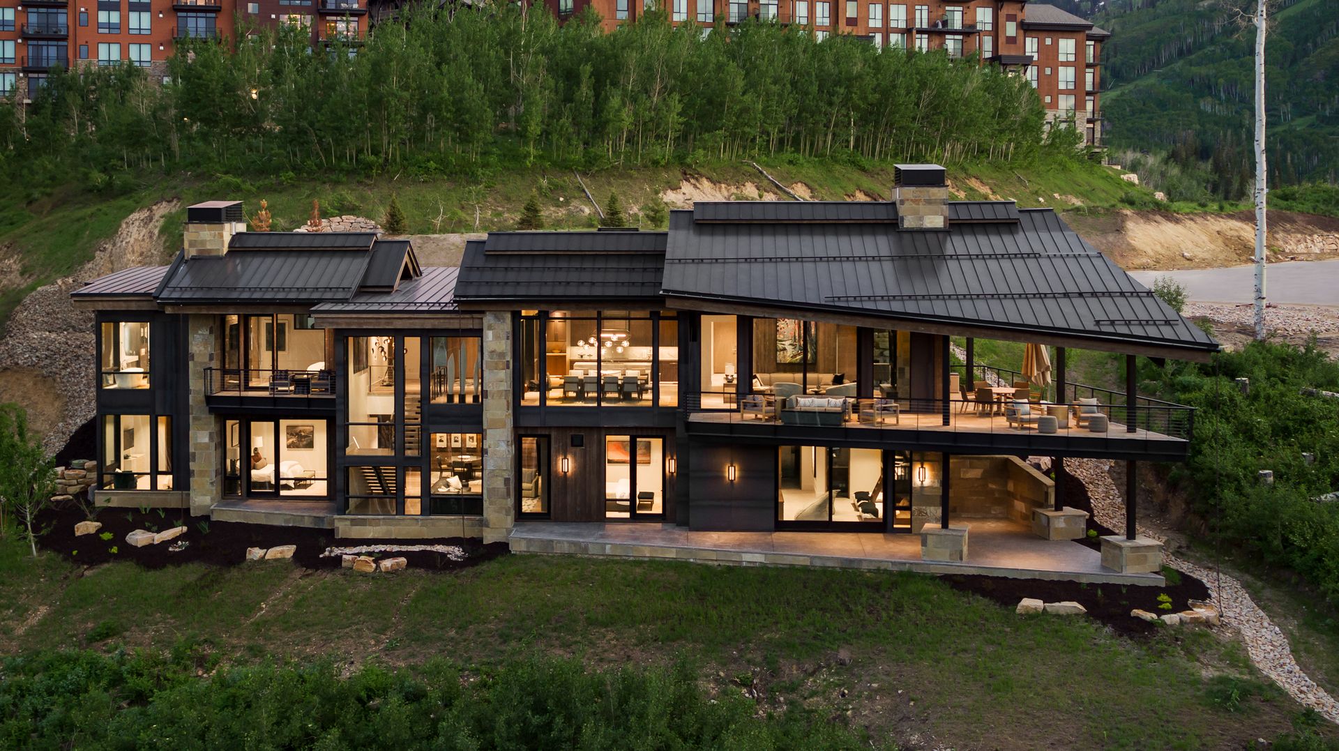 A large house is sitting on top of a hill surrounded by trees.