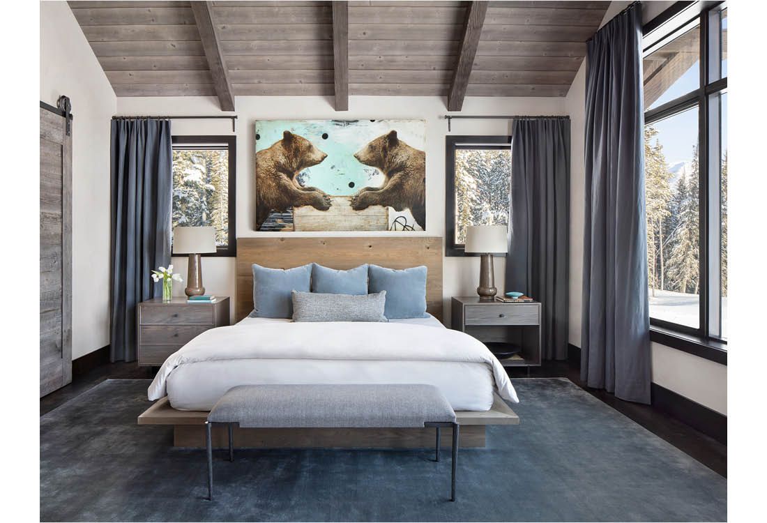 A bedroom with a bed , nightstands , lamps and a painting of two bears on the wall.