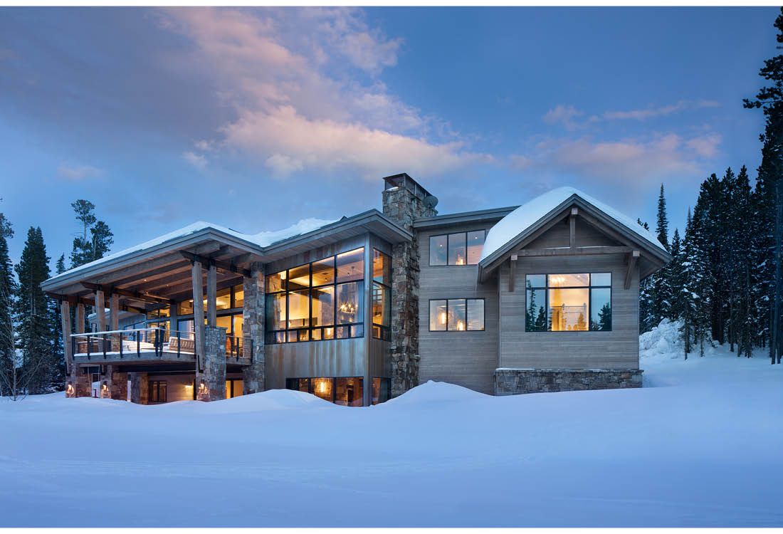 A large house is sitting in the middle of a snow covered field.