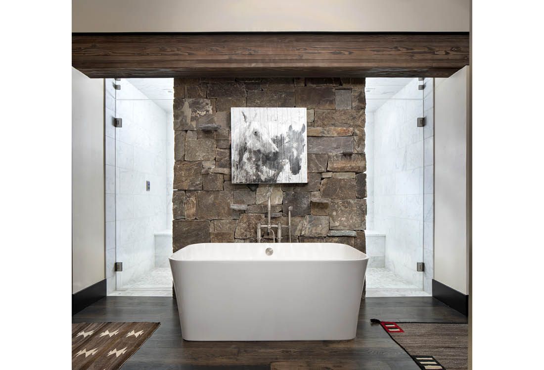 A bathroom with a bathtub and a stone wall.