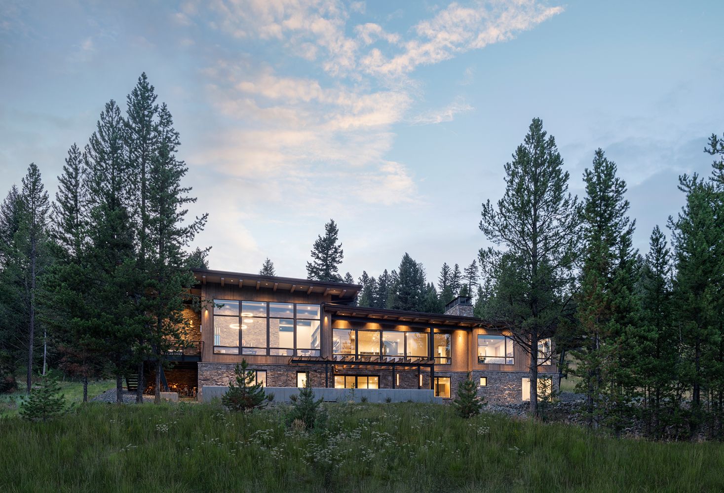 A large house is surrounded by trees in a field.