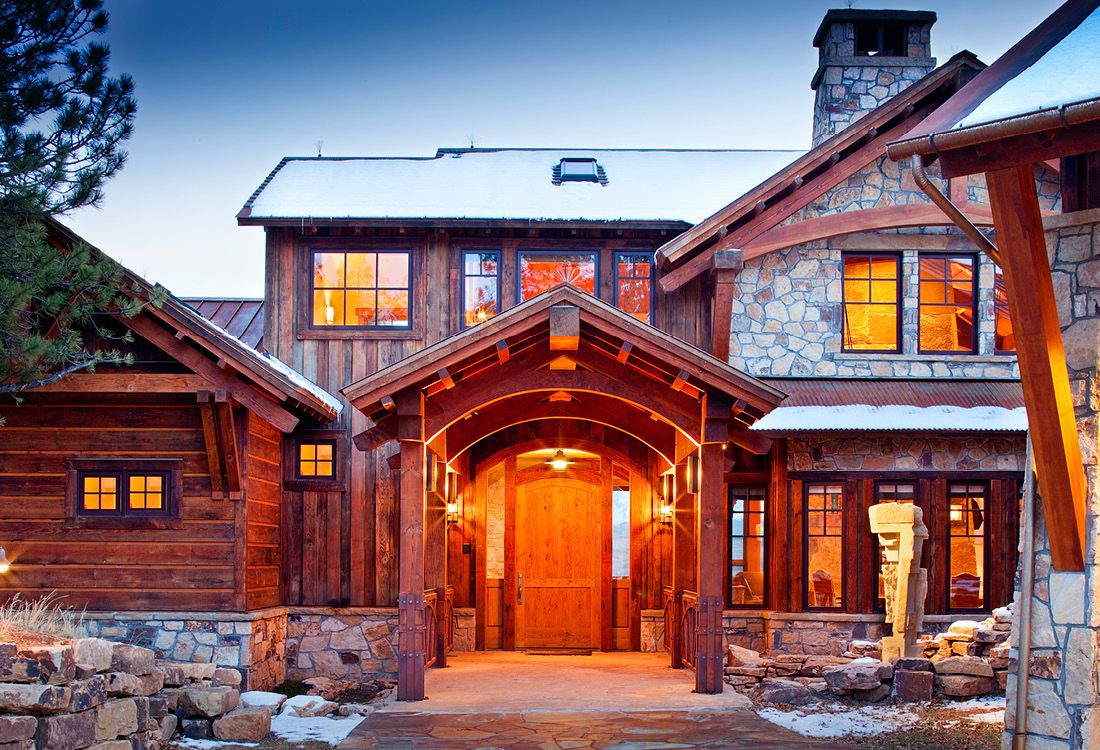 The front of a large wooden and stone house with a large wooden door.
