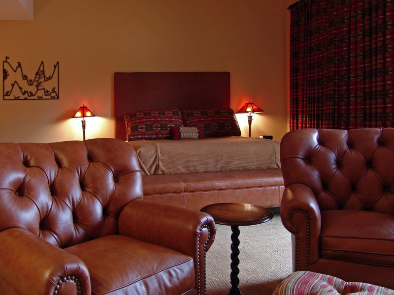 A bedroom with two brown leather chairs and a bed