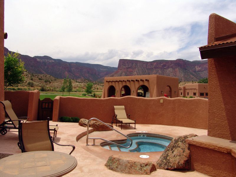 A patio with a hot tub and chairs with mountains in the background