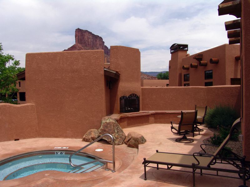 A patio with a hot tub and chairs in front of a building
