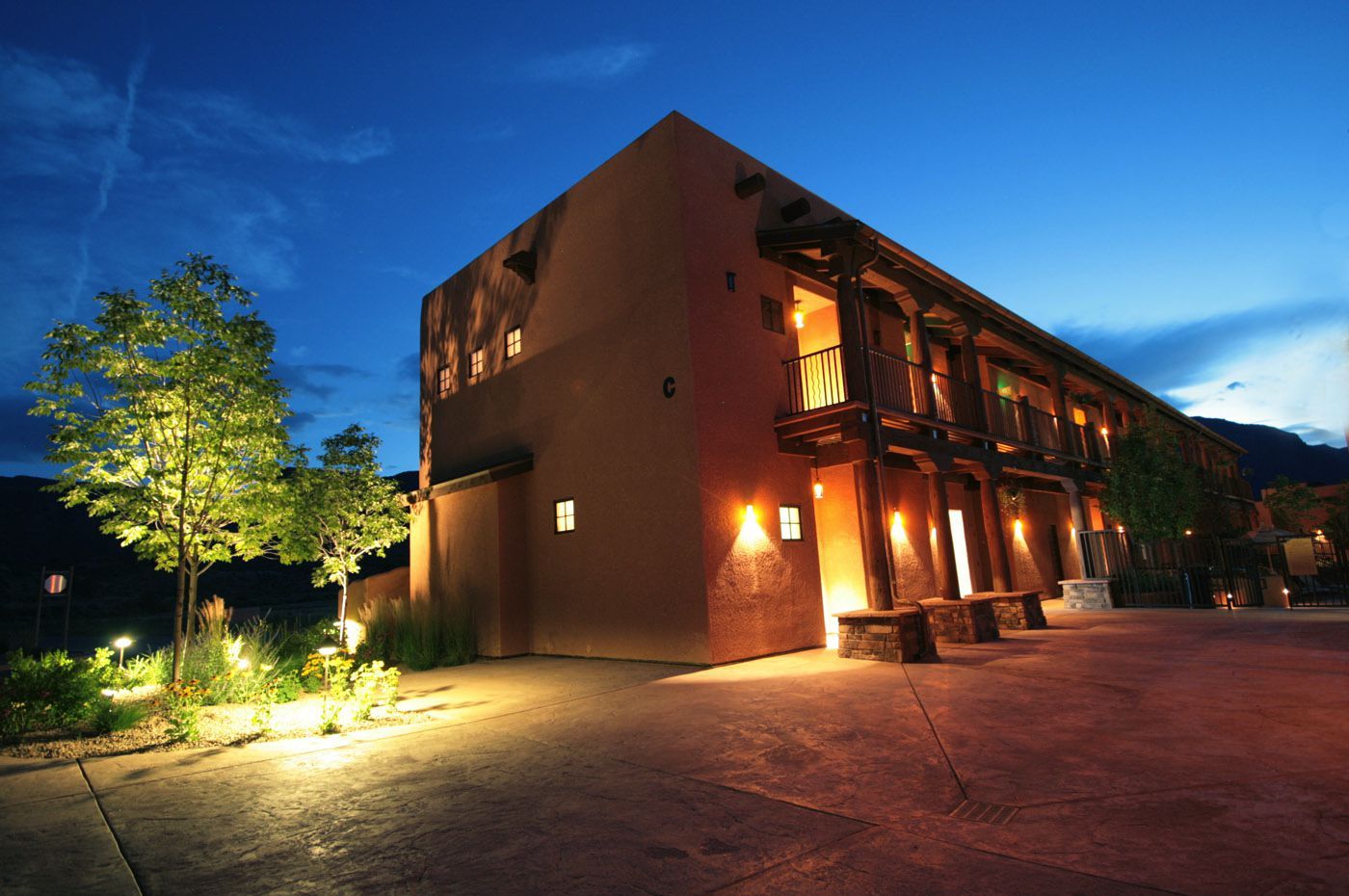 A large building is lit up at night with a blue sky in the background